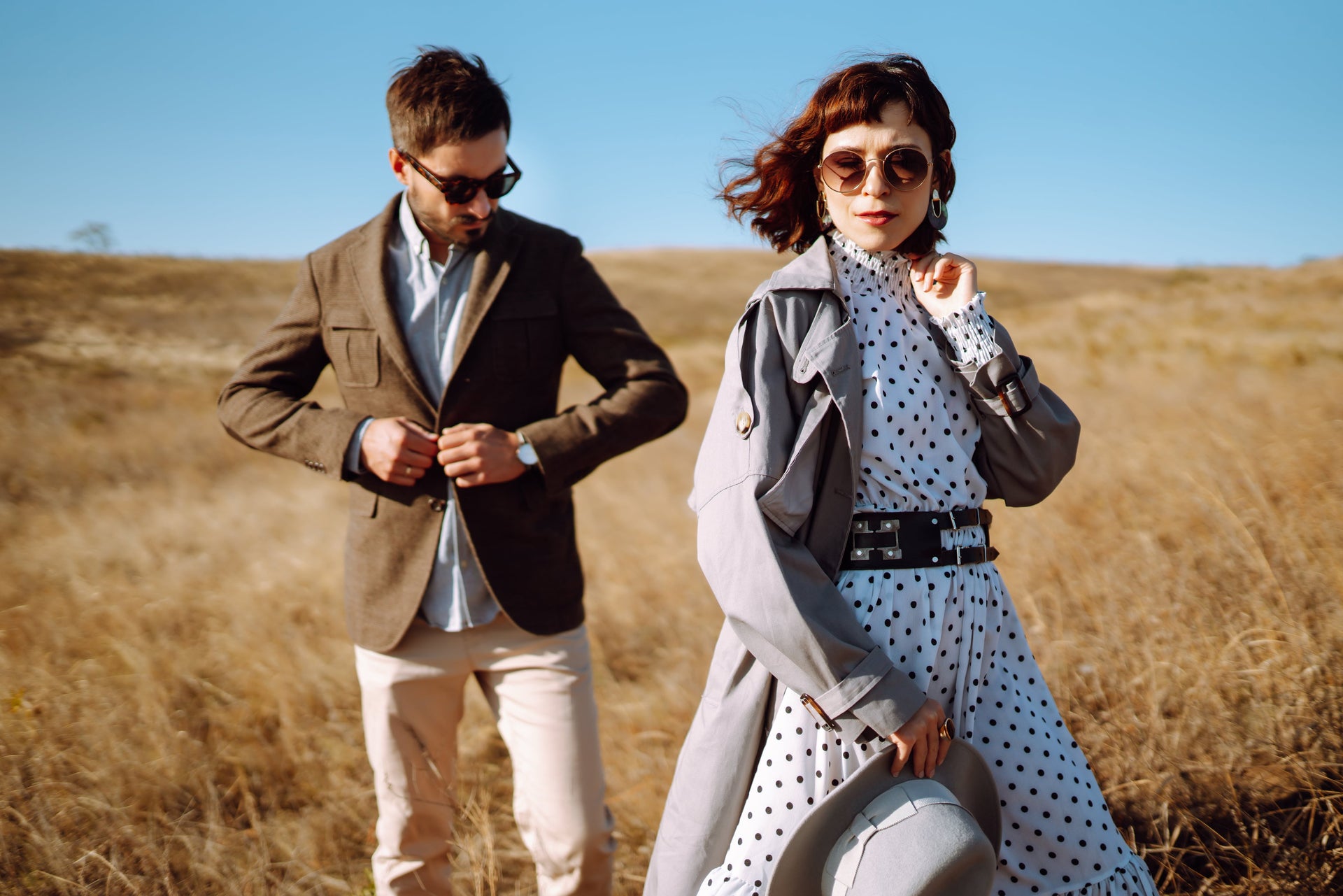 Stylish couple in coordinated outfits with polka dot patterns and blazers in outdoor setting
